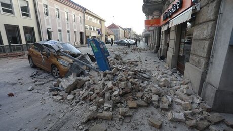 In Kroatien bedecken Trümmer eines eingestürzten Hauses ein Fahrzeug. / © Marin Tironi/Pixsell/Xinhua (dpa)