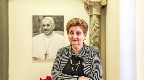 Mariella Enoc steht vor einem Porträt von Papst Franziskus / © Stefano dal Pozzolo (KNA)