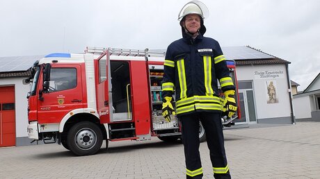 Oliver Stutzky in seiner Monatur als Feuerwehrmann / © Christopher Beschnitt (KNA)