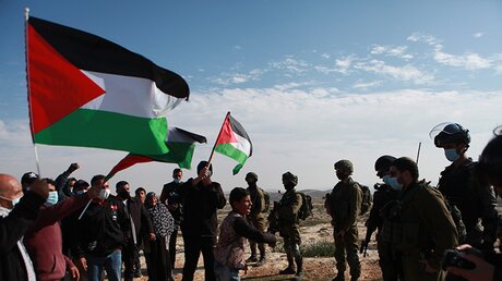 Palästinenser protestieren mit Nationalflaggen vor israelischen Soldaten / © Mamoun Wazwaz (dpa)
