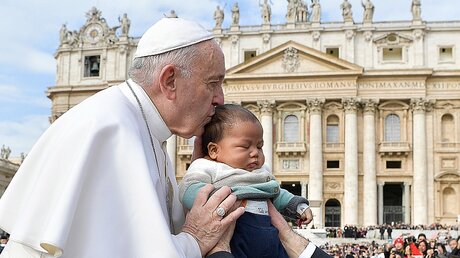 Papst Franziskus küsst ein Kind während der Generalaudienz auf dem Petersplatz / © Vatican Media/Romanos Siciliani (KNA)