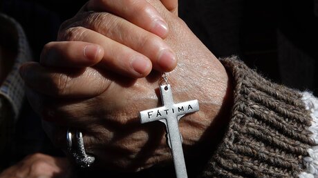 Ein Kreuz in den Händen eines Gläubigen in Fatima (dpa)