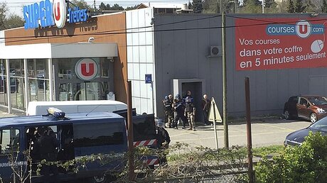 Polizisten stehen in der kleinen Ortschaft am Rande von Carcassonne an einer Seitentür eines Supermarktes / © Newsflare/Tarbouriech Roseline (dpa)