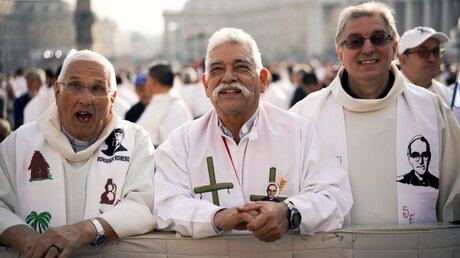 Priester tragen Gewänder mit dem Bildnis von Oscar Romero / © Andrew Medichini (dpa)