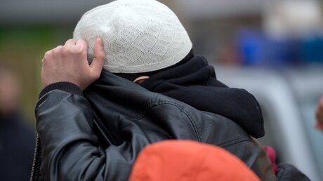 Ein Mann aus dem Umfeld der Koran-Verteilaktion verdeckt sein Gesicht / © Boris Roessler (dpa)