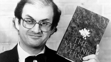 Salman Rushdie mit seinem Buch der "Satanischen Verse" vom 14.02.1989 in London / © Keystone (epd)
