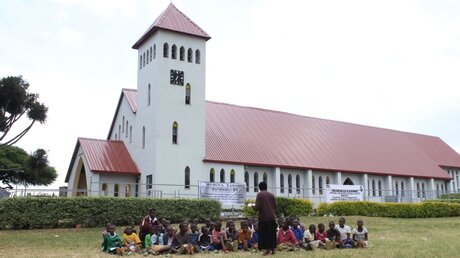 Unterricht vor der katholischen Kirche in Kibuye in Ruanda. Eine Schulklasse sitzt draußen auf der Wiese, der Lehrer unterrichtet.  / © Markus Harmann (KNA)