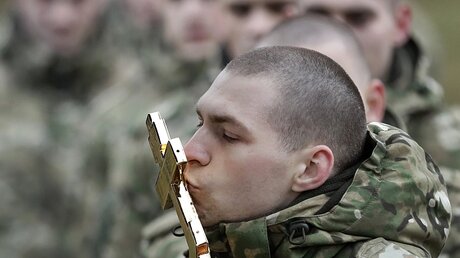 Soldaten einer Spezialeinheit des weißrussischen Innenministeriums küssen ein Kreuz / © Sergei Grits (dpa)