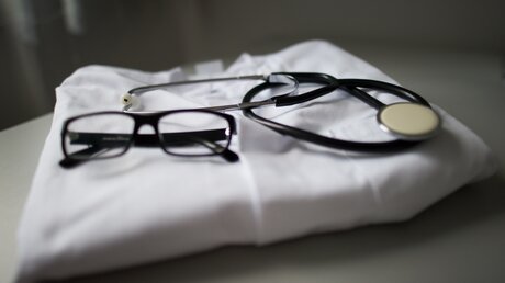 Stethoskop und Brille auf einem Arztkittel / © Arno Burgi (dpa)