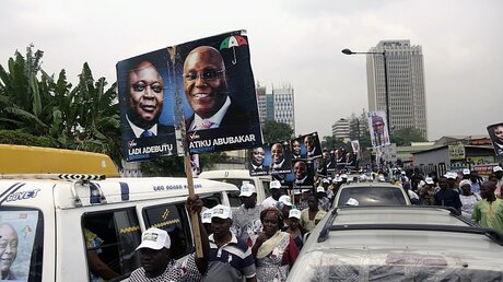 Teilnehmer einer Wahlkampfveranstaltung kommen mit Plakaten des nigerianischen Präsidentschaftskandidaten Abubakar (r) / © Sunday Alamba (dpa)