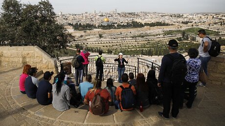 Touristen sitzen auf Stufen an einer Aussichtsplattform vor dem Panorama von Jerusalem mit Felsendom am 5. Februar 2018, bei einer Führung auf dem Ölberg.  / © Corinna Kern (KNA)