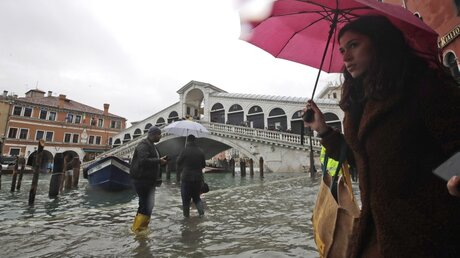 Venedig: Passanten gehen in der Nähe der Rialto-Brücke durch das Hochwasser / © Luca Bruno (dpa)