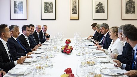 Viktor Orban und Angela Merkel sitzen zusammen mit Delegierten an einer Tafel / © Balazs Szecsodi (dpa)