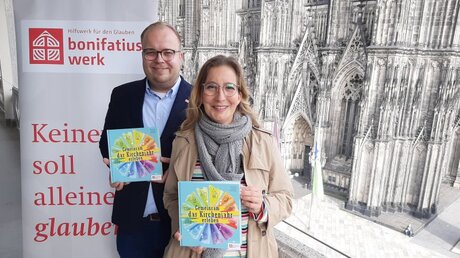 Yvonne Willicks und Julian Heese stellen neues Kirchenjahrbuch vor dem Kölner Dom vor (Bonifatiuswerk)