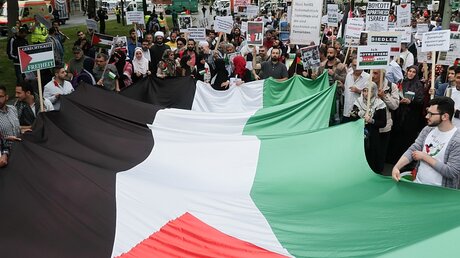 Zahlreiche Menschen nehmen an einer anti-israelischen Demonstration anlässlich des sogenannten Al-Kuds-Tage teil, einige tragen eine übergroße Flagge Palästinas (Archiv) / © Jörg Carstensen (dpa)
