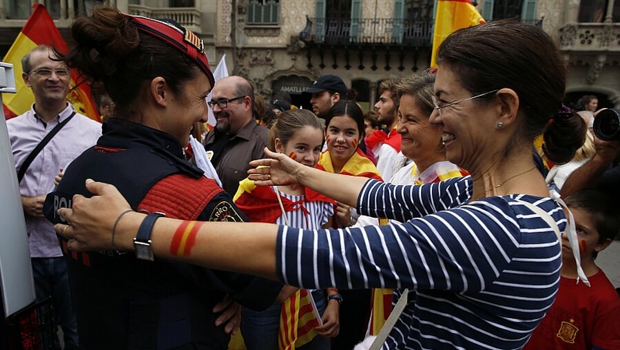 Am spanischen Nationalfeiertag: Eine Spanierin umarmt eine Polizistin der katalanischen Regionalpolizei / © Manu Fernandez (dpa)