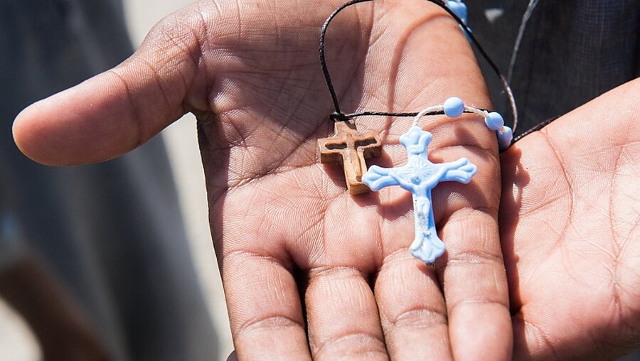 Flüchtling hält Kreuzanhänger in der Hand / © Elisabeth Schomaker (KNA)
