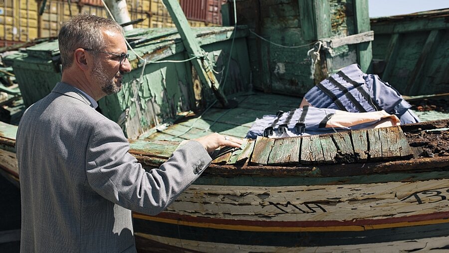 Erzbischof Stefan Heße schaut sich auf Sizilien ein altes Flüchtlingsboot an / © Joern Neumann (DBK)