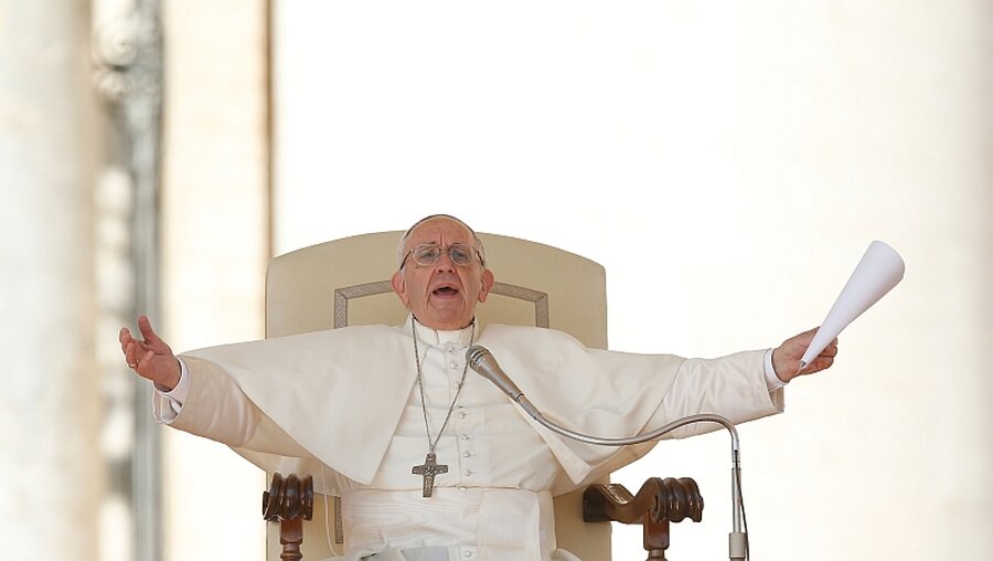 Papst Franziskus breitet seine Arme aus und deutet eine Umarmung an / © Paul Haring (KNA)