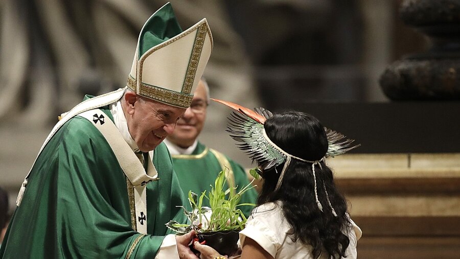 Abschlussmesse Amazonas-Synode: Ein Mädchen aus Amazonien überreicht Papst Franziskus eine Pflanze / © Alessandra Tarantino (dpa)