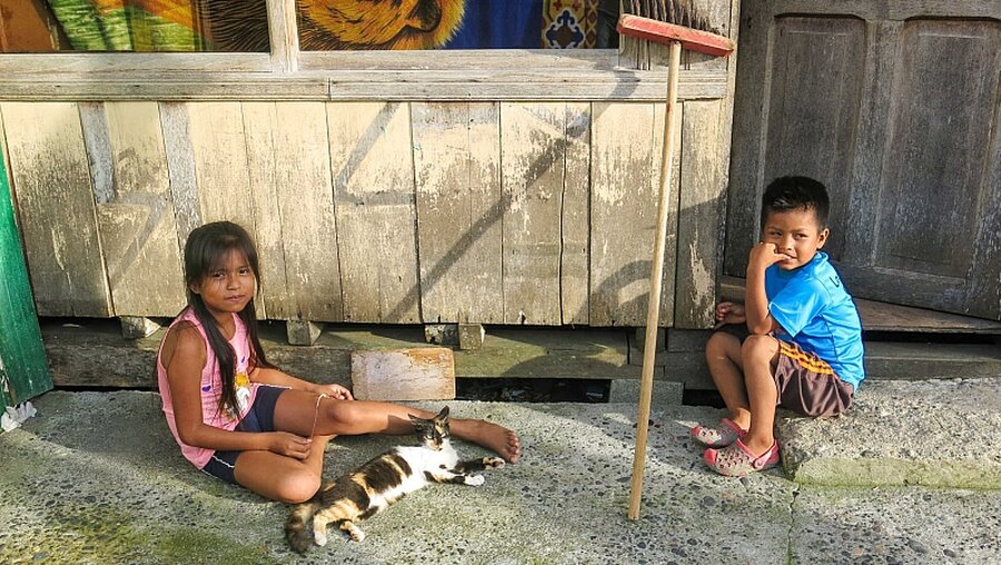 Bedrohter Lebensraum: Zwei Kinder sitzen vor einer einfachen Holzhütte in Ecuador / © Alexander Pitz (KNA)