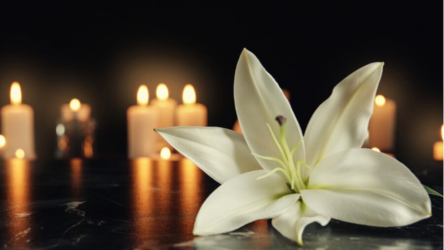 Beerdigungssymbole: Weiße Lilie und Kerzen (shutterstock)