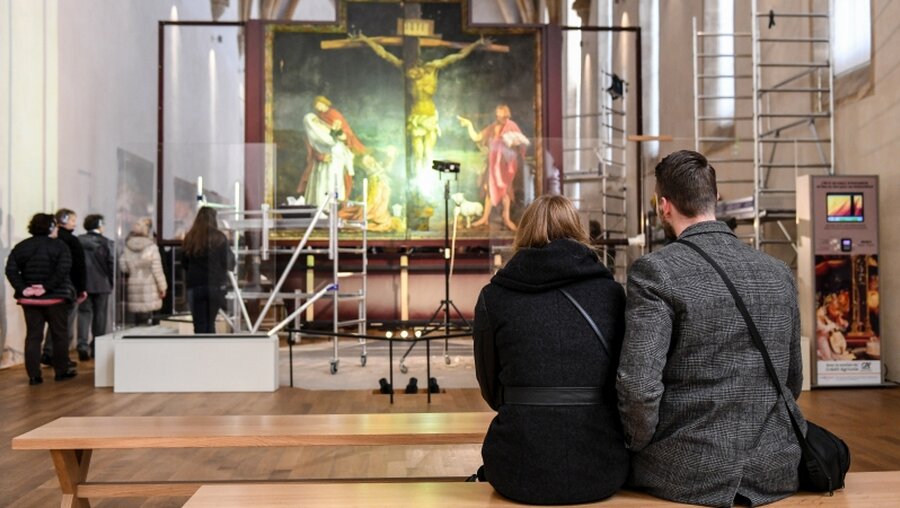 Besucher betrachten die Restaurierung der Bildtafel der Kreuzigung während der Restaurierungsarbeiten am Isenheimer Altar / © Harald Oppitz (KNA)
