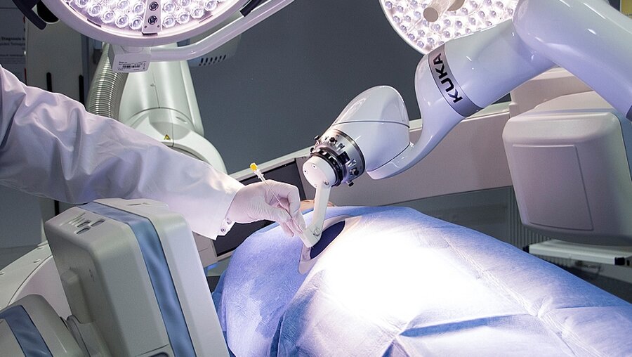 Menschenhand und Roboterarm bei einer Biopsie / © N.N. (dpa)