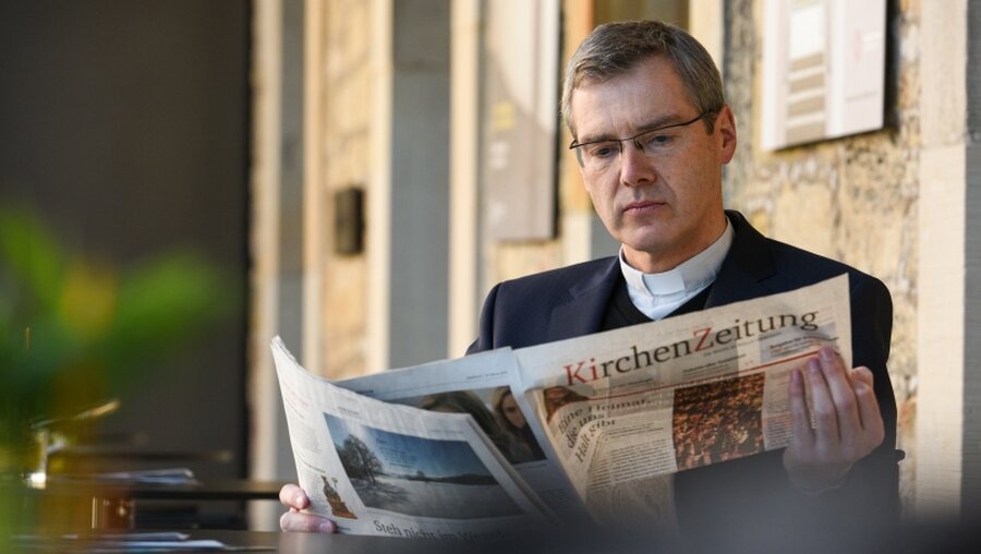 Bischof Heiner Wilmer studiert eine Kirchenzeitung / © Harald Oppitz (KNA)