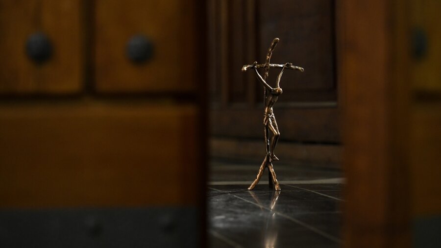 Blick durch eine leicht geöffnete Kirchentür auf ein Kruzifix / © Harald Oppitz (KNA)