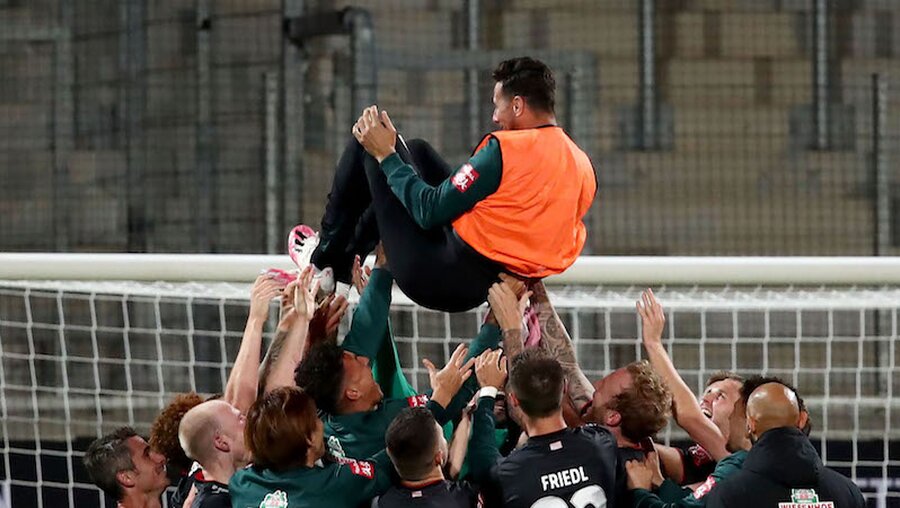 Bremens Claudio Pizarro wird nach Spielende von seinen Teamkollegen in die Luft geworfen. / © Tom Weller (dpa)