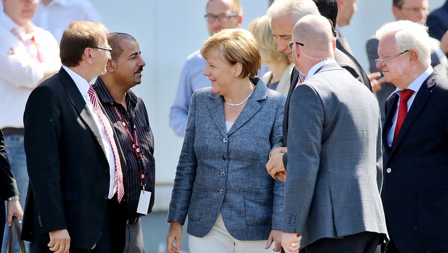 Angela Merkel unterhält sich in Heidenau mit einem Helfer (z.v.l.) (dpa)