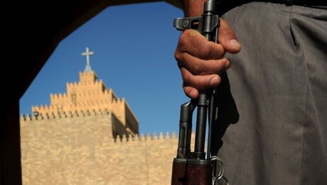Bewaffneter Mann vor einer Kirche / © Katharina Ebel (KNA)