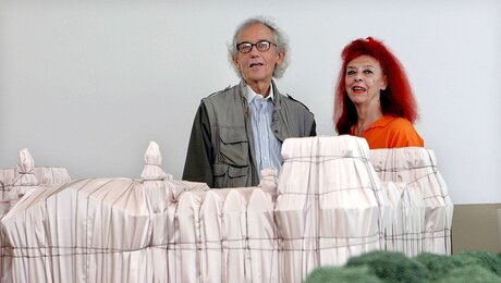 Christo und Jean-Claude hinter einem Modell des verhüllten Reichtstags / © Raquel Manzanares (dpa)