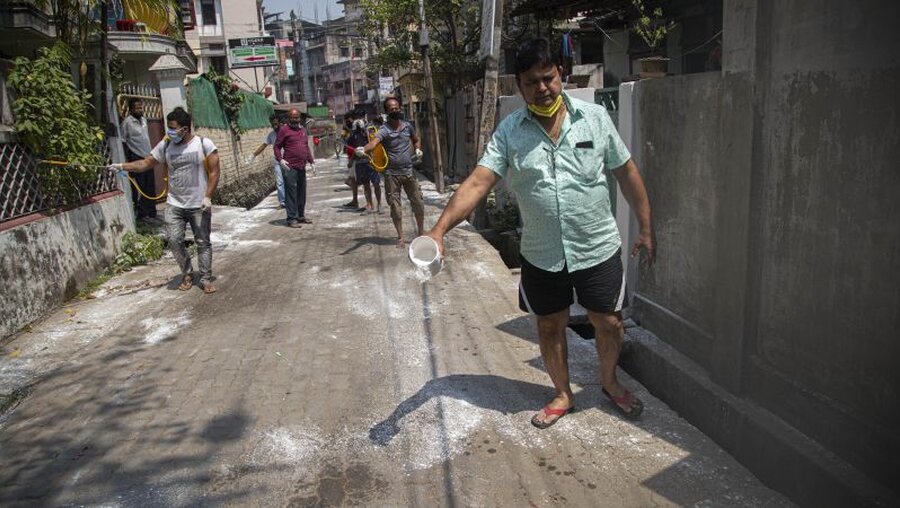 Coronavirus - Indien: Einwohner mit Mundschutz desinfizieren ihre Straßen, um die Ausbreitung des Coronavirus einzudämmen / © Anupam Nath (dpa)