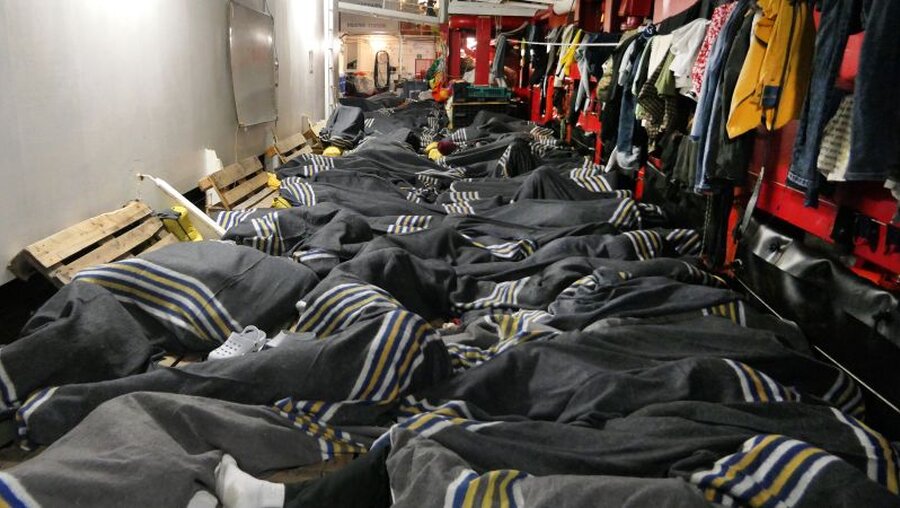 In Decken gehüllt liegen dicht an dicht Menschen an Bord des Rettungsschiffes "Ocean Viking" / © Julia Schäfermeyer (dpa)