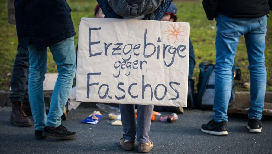 Gegendemonstranten halten ein Schild mit der Aufschrift "Erzgebirge gegen Faschos" / © Oliver Killig (dpa)