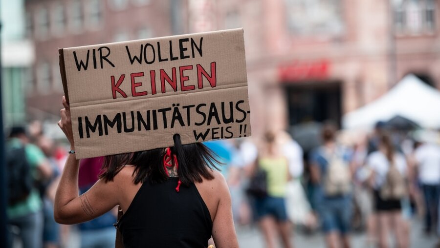 Demonstrantin mit Schild "Wir wollen keinen Immunitätsausweis" / © Fabian Strauch (dpa)
