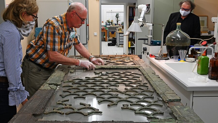 Der Restaurator des Landesmuseums Mainz, Hans-Peter Schnellbächer, untersucht Details einer Bronzetür der Römerzeit / © Peter Zschunke (dpa)