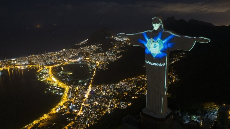 Die Christus-Erlöser-Statue in Rio ist beleuchtet, als ob sie eine Mundschutzmaske tragen würde / © Leo Correa (dpa)