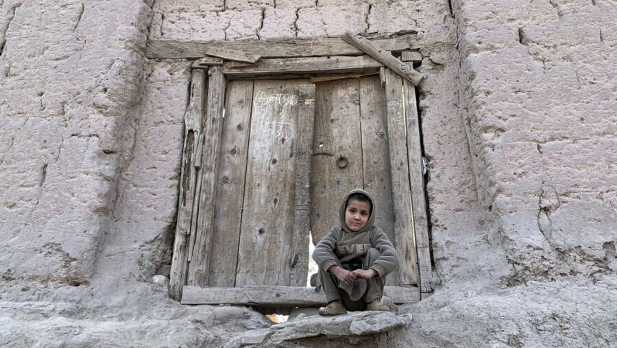 Ein afghanischer Junge sitzt vor seinem Haus / © Rahmat Gul (dpa)