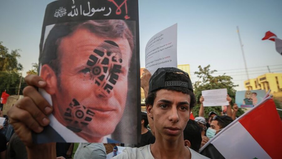 Ein Demonstrant hält ein mit einem Schuhabdruck gestempeltes Bild des französischen Präsidenten Macron / © Ameer Al Mohammedaw (dpa)