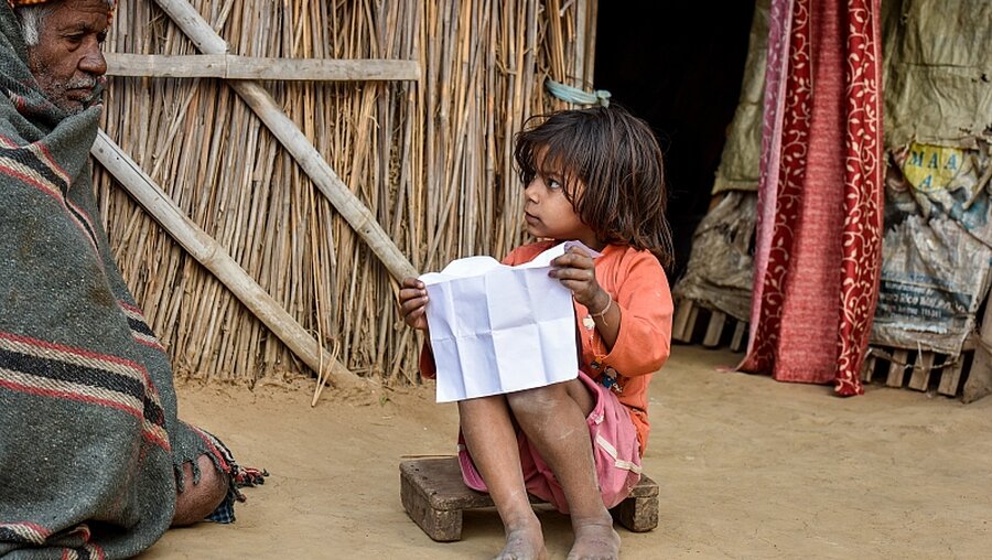 Ein Kind und ein alter Mann im Armenviertel, Indien / © Gottfried Bohl (KNA)