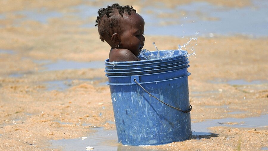 Ein kleines Kind spielt mit einem Eimer Wasser in Beira, Mosambik / © Tsvangirayi Mukwazhi (dpa)