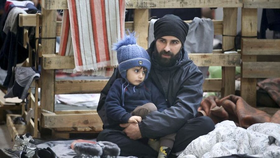 Ein Mann und sein Kind harren bei eisigen Temperaturen im Grenzgebiet aus / © Leonid Shcheglov (dpa)
