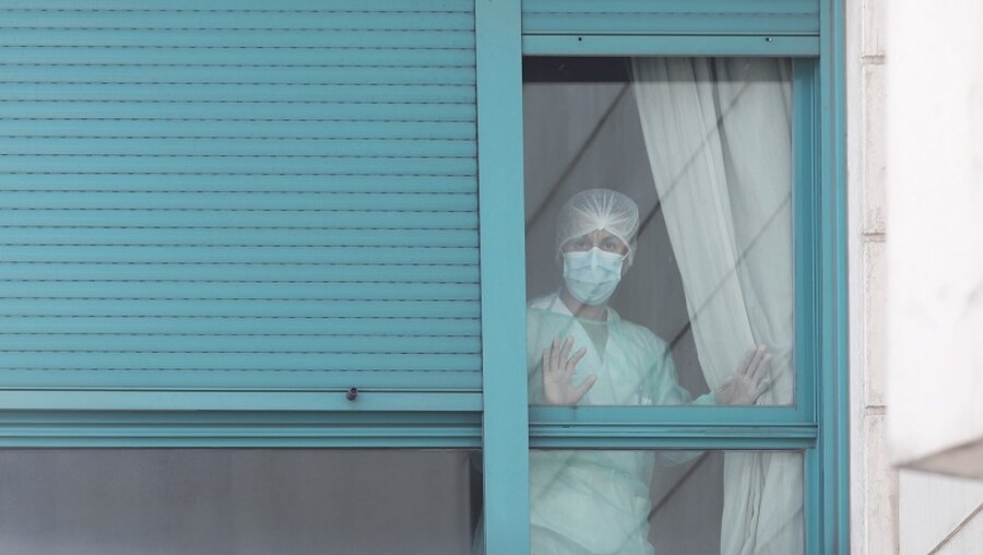 Ein Mitglied des Gesundheitspersonals schaut aus dem Fenster eines Pflegeheims in Madrid / © Eduardo Parra (dpa)