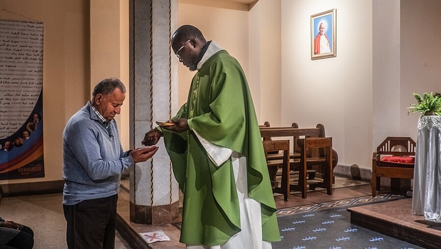 Ein Priester spendet einem Mann die Kommunion / © Alessio Mamo (KNA)