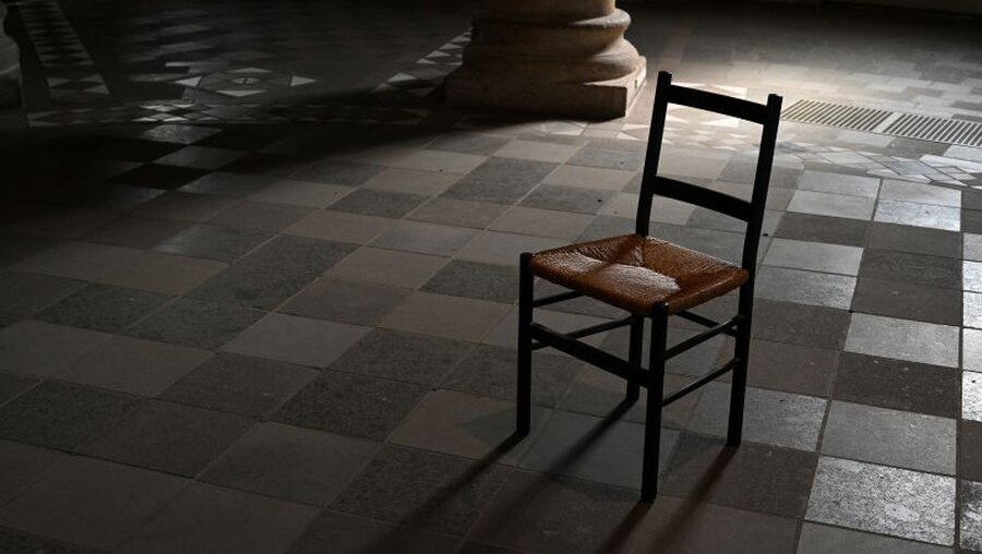 Ein Stuhl steht in einer dunklen Kirche / © Harald Oppitz (KNA)