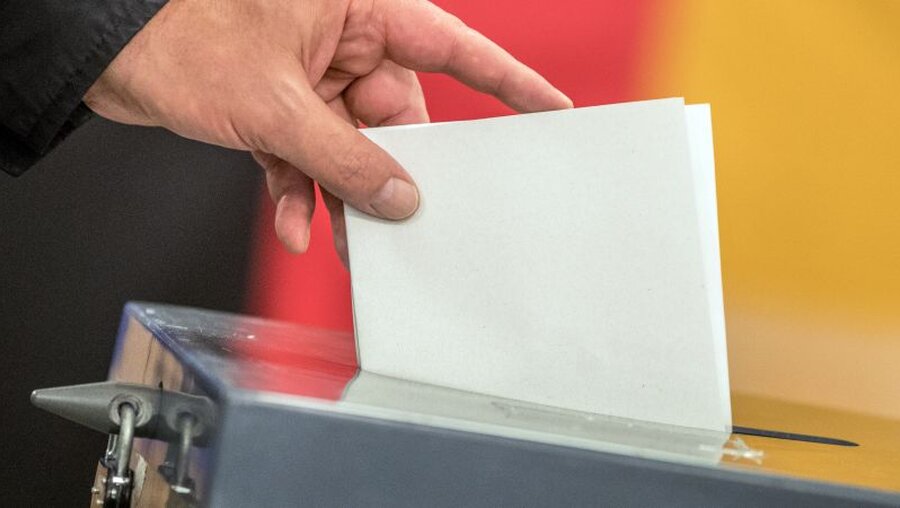 Ein Wähler wirft seinen Stimmzettel in eine Wahlurne / © Michael Kappeler (dpa)