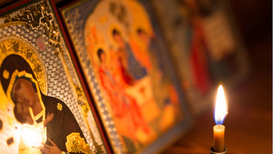 Eine brennende Kerze mit orthodoxen Darstellungen (shutterstock)